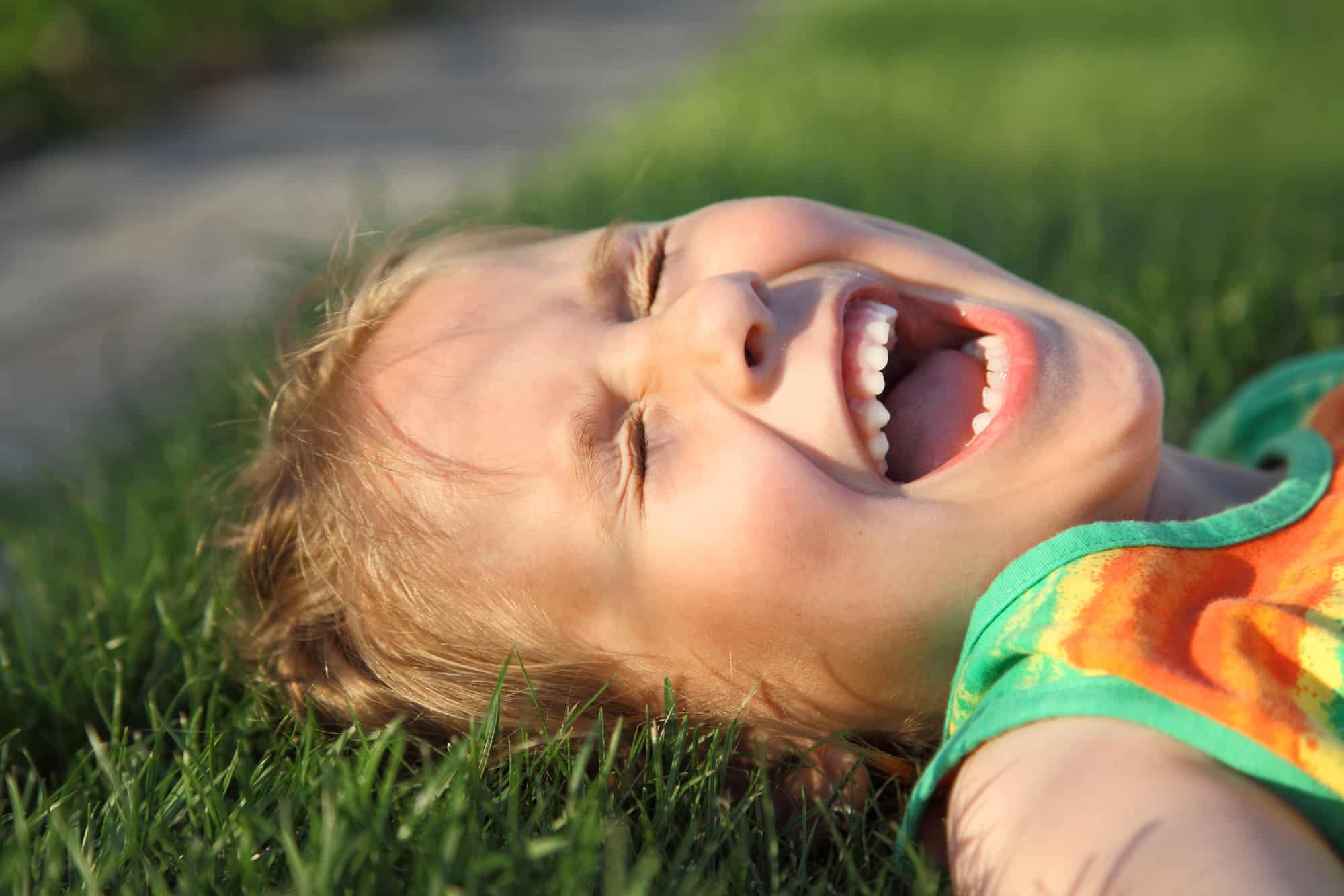 Happy cute girl laughing on a grass field
